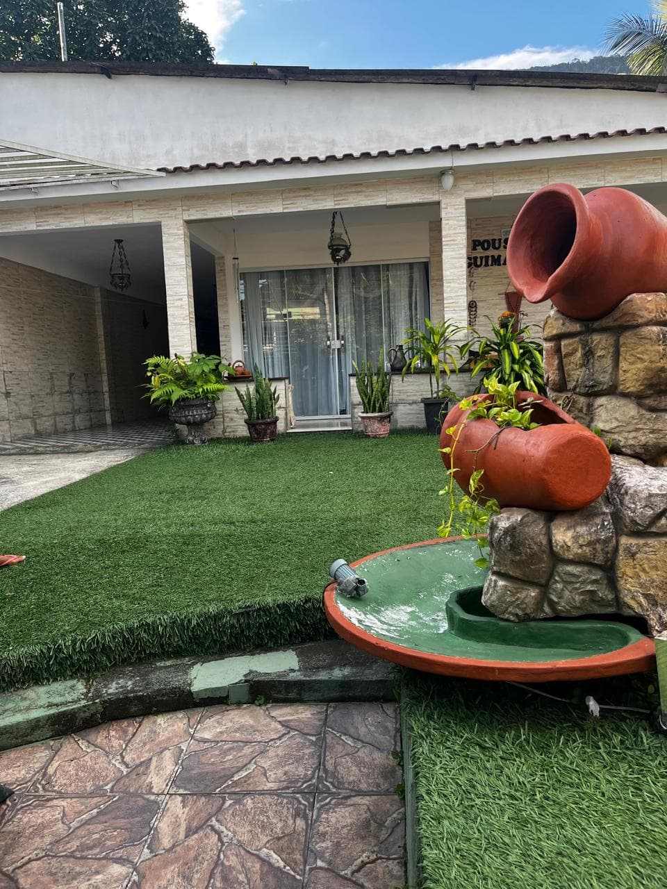 Jardim com fonte e fachada da Pousada Guimarães